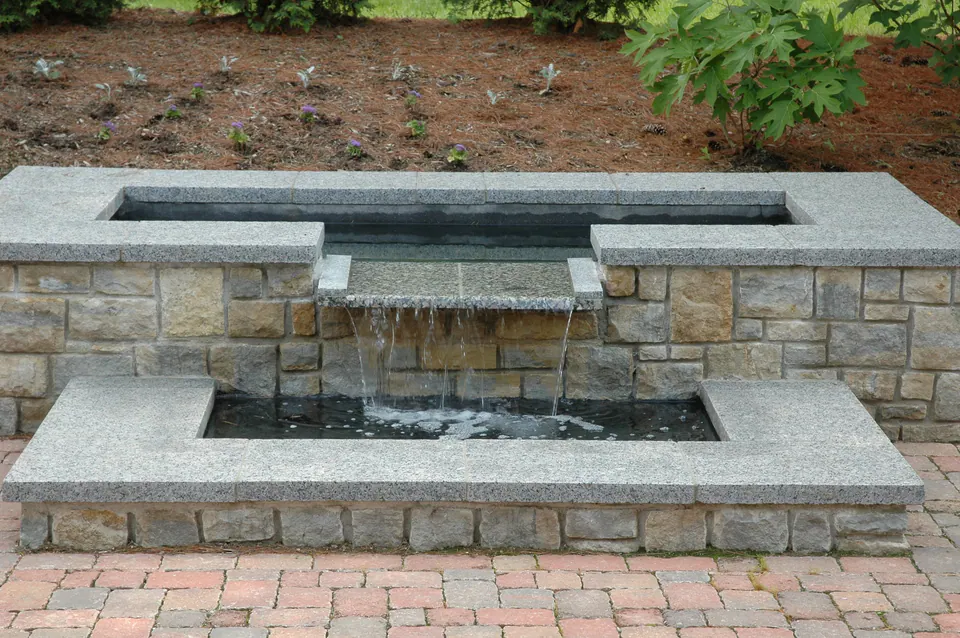 Two-level cut stone basin with water spilling from the upper pool to the lower pool